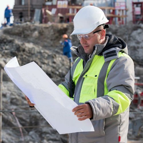 Construction workers reviewing blueprints on site